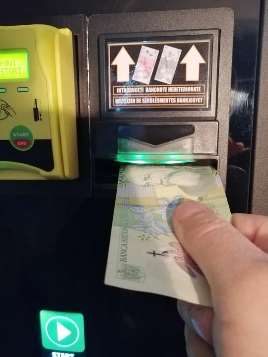 Bancnota intră în acceptor; alături, butonul START al ecranului